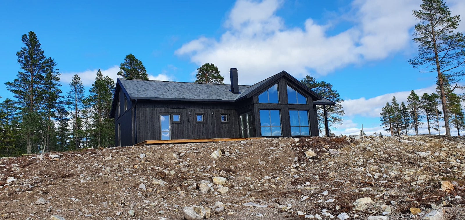 Priekšējais skats uz moderno privātmāju ar lieliem logiem un dedzināta koka imitācijas fasādi