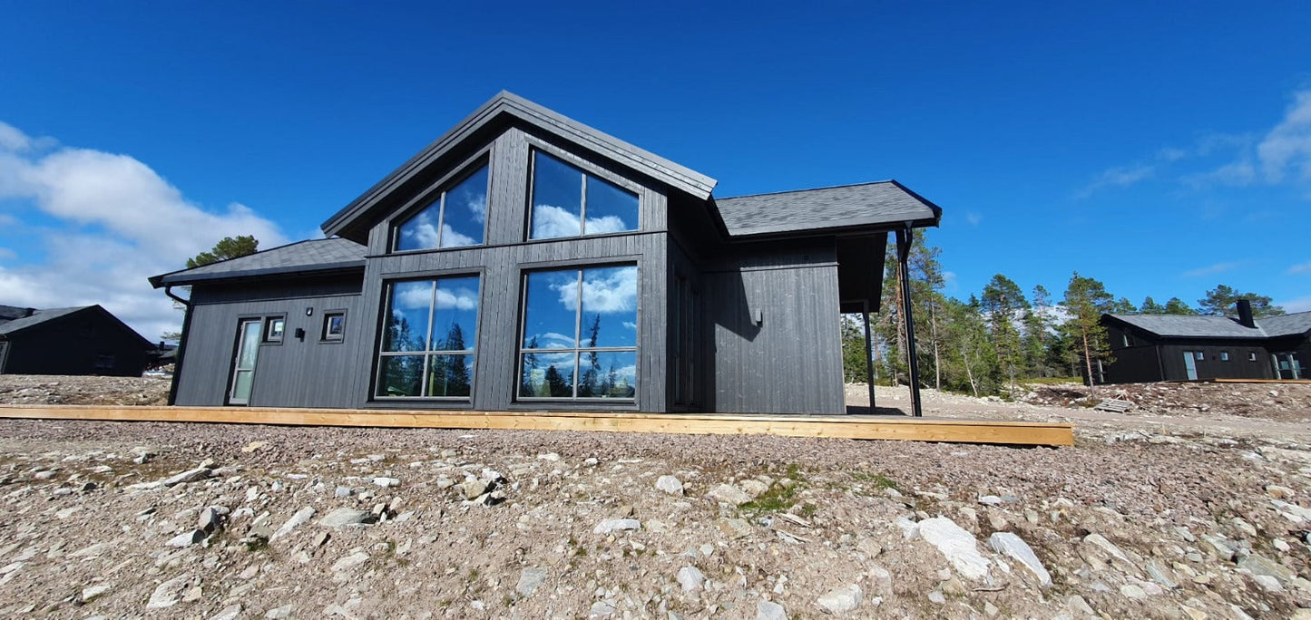 Priekšējais skats uz modernu privātmāju ar lieliem panorāmas logiem un dedzināta koka imitācijas fasādi